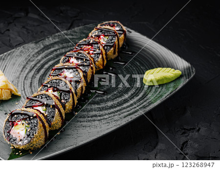 Sushi rolls with black sesame and drizzled sauce on a dark plate Sushi rolls with black sesame and drizzled sauce on a dark plate 123268947