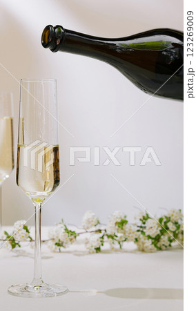 Celebratory drink being poured into a flute glass with flowers 123269009