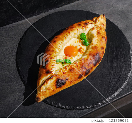 Delicious freshly baked khachapuri served on a black stone plate Delicious freshly baked khachapuri served on a black stone plate 123269051