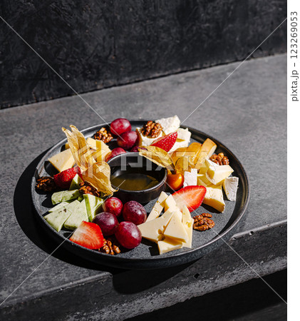 Cheese and fruit platter served on a sleek dark surface Cheese and fruit platter served on a sleek dark surface 123269053