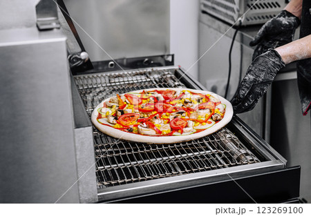 Pizza baking process in a commercial kitchen at lunchtime rush 123269100