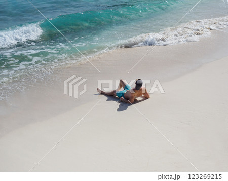 Handsome man sitting on stunning white sand beach Handsome man sitting on stunning white sand beach 123269215