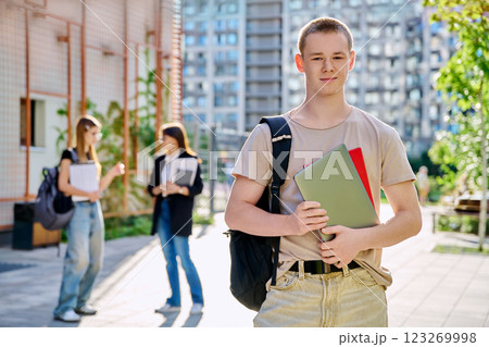 Portrait of college student guy looking at camera outdoor near educational building 123269998