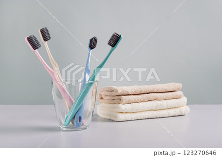 Clean toothbrushes in a transparent glass and towels on the table 123270646