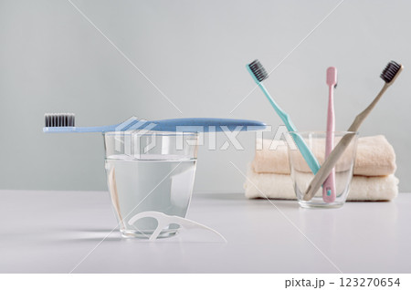 Toothbrush on a glass of water, disposable dental floss in the bathroom Toothbrush on a glass of water, disposable dental floss in the bathroom 123270654