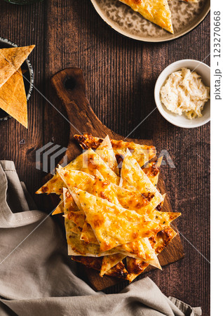 Homemade pita nachos with cheese and garlic on a board on a table top and vertical view 123270668