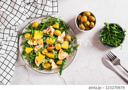 Vegetarian salad with cauliflower, orange, arugula and olives on a plate top view Vegetarian salad with cauliflower, orange, arugula and olives on a plate top view 123270676
