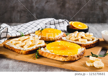Crispy sandwiches with cottage cheese and fruits on a board on a table 123270681
