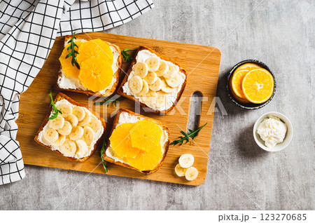 Crispy sandwiches with cottage cheese and fruits on a board on a table top view Crispy sandwiches with cottage cheese and fruits on a board on a table top view 123270685