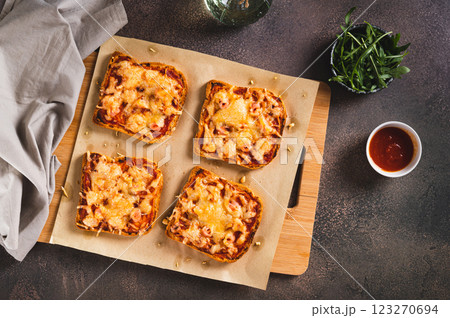 Baked sandwiches with bacon, cheese and tomato sauce on a board on a table top view 123270694