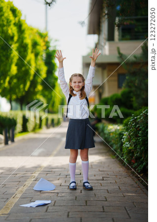 Happy cute schoolgirl dropping notebooks at the end of the school year. 123272050