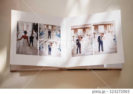 an open photo book with wedding photos on a white table 123272063