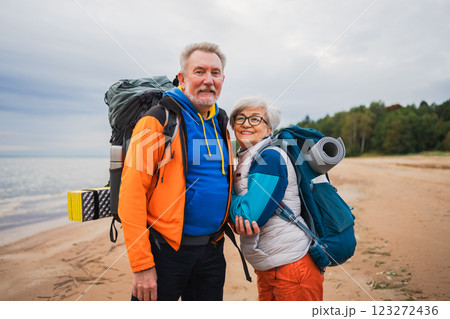 Hiking tourism adventure. Senior couple man woman enjoying outdoor recreation hiking on beach. Happy old people backpackers hikers enjoy walking hike trekking tourism active vacation beauty of nature 123272436