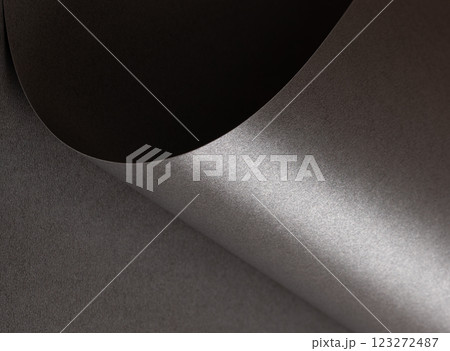 Charcoal gray paper background with a pearlescent, glossy texture and shimmering wavy edges. Deep 123272487