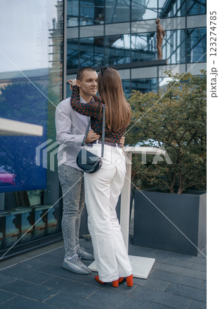 Romantic scene of a couple of lovers sitting at a table outside a cafe. The man and woman are kissing gently, holding hands, which emphasizes their closeness and intimacy. Romantic scene of a couple of lovers sitting at a table outside a cafe. The man and woman are kissing gently, holding hands, which emphasizes their closeness and intimacy. 123274785