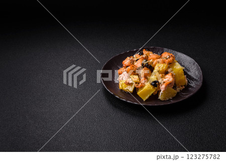 Baked salmon pieces with potatoes, cheese and olives 123275782