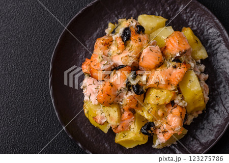 Baked salmon pieces with potatoes, cheese and olives Baked salmon pieces with potatoes, cheese and olives 123275786