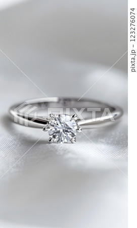 A beautiful solitaire diamond ring, featuring a sparkling gem on a sleek metal band, elegantly showcased on a smooth white surface, perfect for an engagement or wedding proposal 123276074