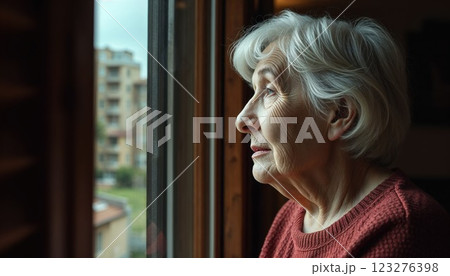 Thoughtful senior woman gazing out the window, lost in reflection. A serene and introspective moment captured through soft natural light, conveying quiet moments of wisdom and aging gracefully 123276398