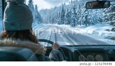 person drives a vehicle along snow-covered roads surrounded by dense trees, embracing a winter road trip adventure in a peaceful, snowy landscape 123276446