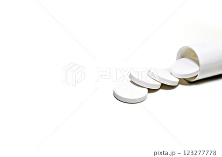 White medicine pills spilling out of a white bottle on white background. White medicine pills spilling out of a white bottle on white background. 123277778