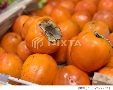 A pile of ripe juicy orange persimmons in a box, on sale at a supermarket vegetable stand, showcases organic, vegetarian and healthy food. Close-up. A pile of ripe juicy orange persimmons in a box, on sale at a supermarket vegetable stand, showcases organic, vegetarian and healthy food. Close-up. 123277864