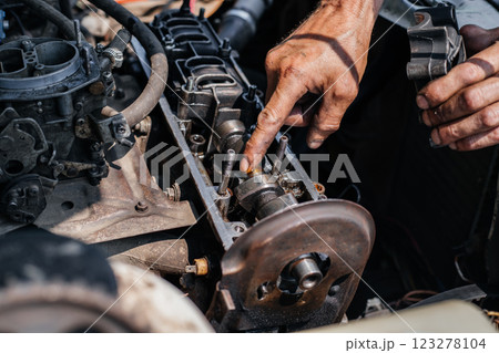 A worker repairs the cylinder head of an automobile engine. Oil removal valve. Car repairs. Car service 123278104
