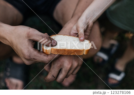 Child gives a homeless poor man a piece of bread in a modern capitalist society. Economic recession, unemployment, poverty, hunger, retirement, global crisis, the concept of the problem of inequality. 123278106