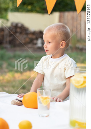 A boy in a yellow T-shirt and with yellow oranges looks away on a warm summer day. 123278166