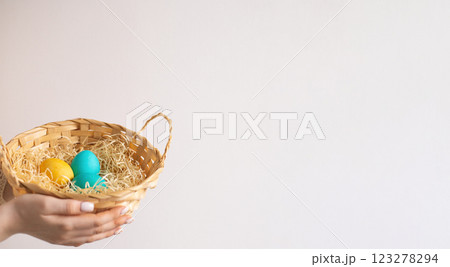 The girl holds a wicker basket with painted eggs. Easter. Copy space The girl holds a wicker basket with painted eggs. Easter. Copy space 123278294