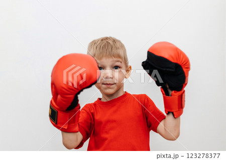 Boy in red boxing gloves on a white background with a scratch on his face. Protection. Self-defense 123278377