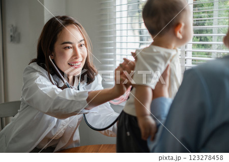 Smiling pediatrician using stethoscope to check baby's health in a sunlit clinic. Smiling pediatrician using stethoscope to check baby's health in a sunlit clinic. 123278458