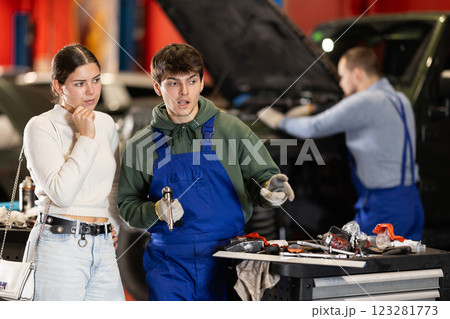Mechanic checking young woman client car in car service center Mechanic checking young woman client car in car service center 123281773