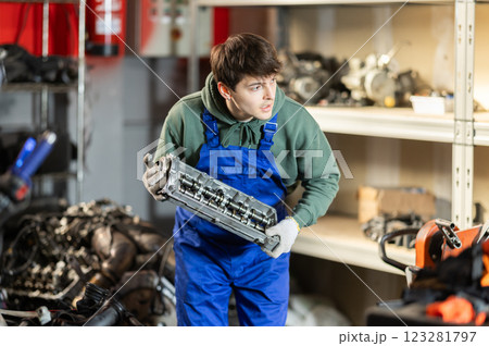 Young auto mechanic repairing an engine in garage 123281797