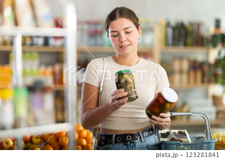Woman make choice choose consider canned vegetables in store 123281841