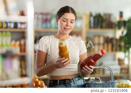 Young woman buyer chooses tomato and peach juices 123281906