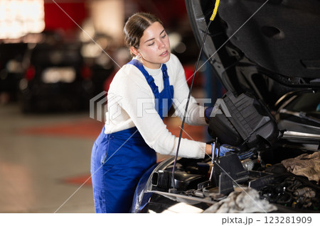 Female mechanic changing air filter in car engine 123281909