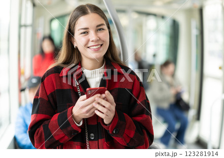 Girl with long hair standing in tram with phone 123281914