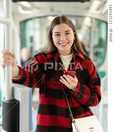 Girl is standing with phone in tram car, getting to work 123281941
