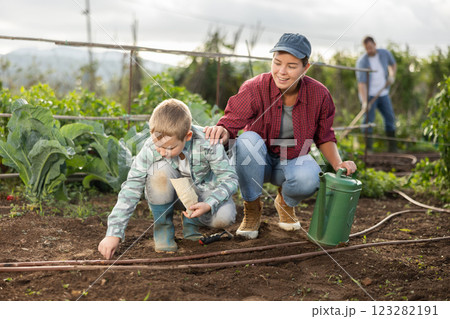 Young woman with boy planting seeds in field 123282191