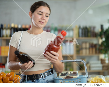 Girl hold packages bottles and choose consider juice in store Girl hold packages bottles and choose consider juice in store 123282468