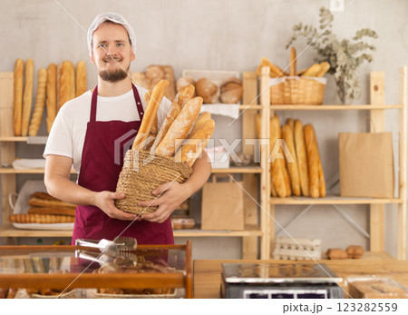 Young male seller with baguettes in basket 123282559
