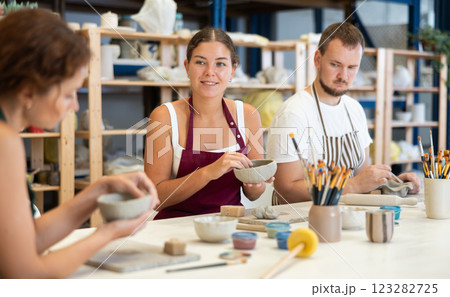 Three pottery workshop workers sculpt from raw clay Three pottery workshop workers sculpt from raw clay 123282725