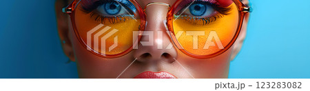 Closeup of woman with amber sunglasses against blue background 123283082