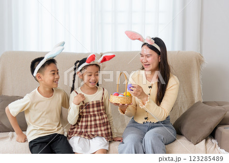 Easter family joy. A cheerful mother and kids with bunny ears celebrate Easter at home 123285489