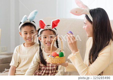 Easter family joy. A cheerful mother and kids with bunny ears celebrate Easter at home Easter family joy. A cheerful mother and kids with bunny ears celebrate Easter at home 123285490