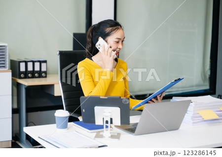 Asian Businesswoman Analyzing Finance on Tablet and Laptop at modern Office Desk tax 123286145
