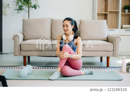 Asian Woman Doing Yoga and Watching Online Tutorials on tablet, Training 123286328