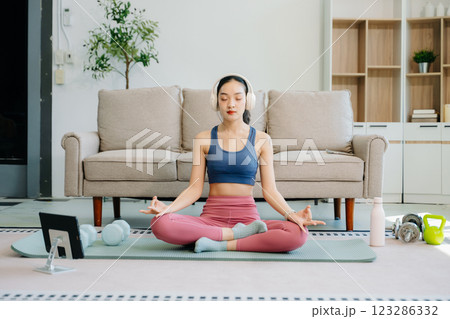 Asian Woman Doing Yoga and Watching Online Tutorials on tablet, Training Asian Woman Doing Yoga and Watching Online Tutorials on tablet, Training 123286332