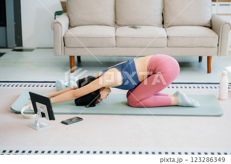 Asian Woman Doing Yoga and Watching Online Tutorials on tablet, Training 123286349